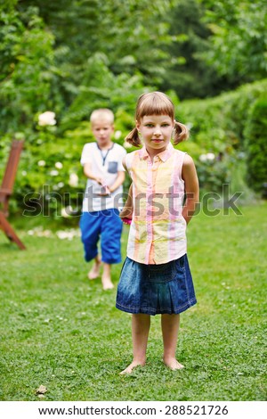 Two children playing together in a garden and pulling a string