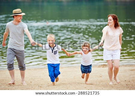 Content family with two children at beach running in summer