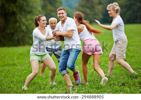 Smiling family playing american football on a meadow in their garden