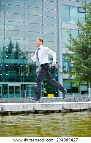 Smiling business man running to appointment in front of office building
