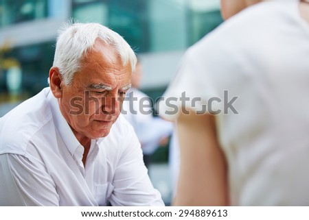 Pensive old business man sitting worried outdoors