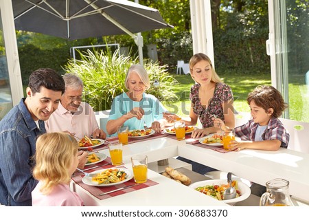 Happy family in three generations eating lunch together in summer