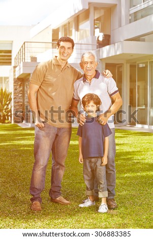 Family with grandfather and grandchild in front of a house in the garden