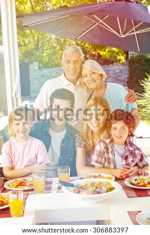 Happy vegan family with grandparents at lunch in summer