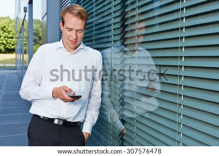 Business man chatting with his smartphone next to his office