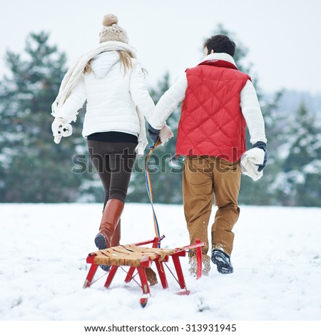 Couple in winter pulling a sled together through snow