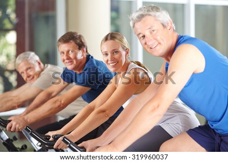 Group of happy seniors on spinning bikes in gym