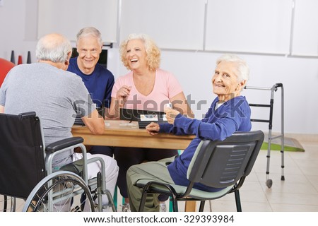 Old woman in nursing home playing with laughing senior people