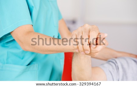 Geriatric nurse holding hands of senior man for consolation