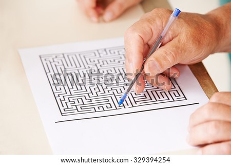 Hand of senior man with pen doing memory training with a paper maze