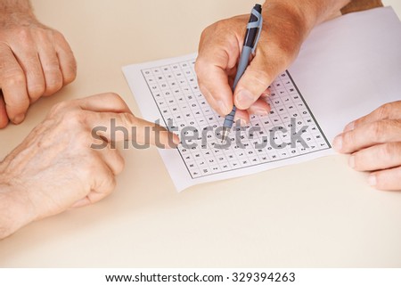 Hands of two senior people solving together a word search quiz