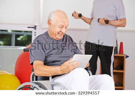 Disabled old man sitting in wheelchair with tablet PC in a nursing home