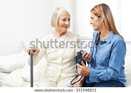 Caregiver doing blood pressure monitoring for senior woman at home