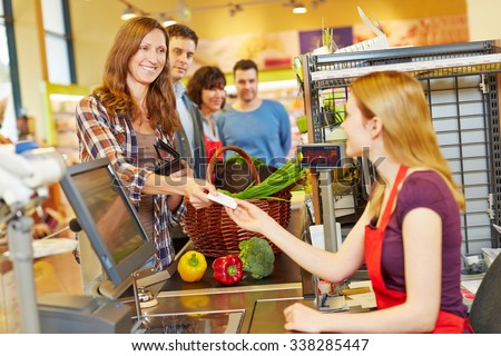 Smiling woman paying with her EC card at supermarket checkout
