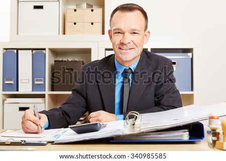 Finance clerk sitting at his desk with files and a calculator