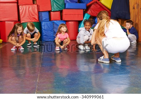Children doing gymnastics in physical education with nursery teacher in preschool