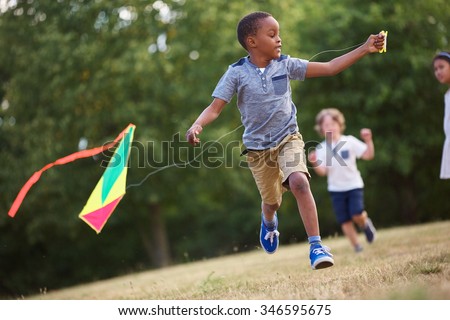 African kid having fun flying a kite in the nature