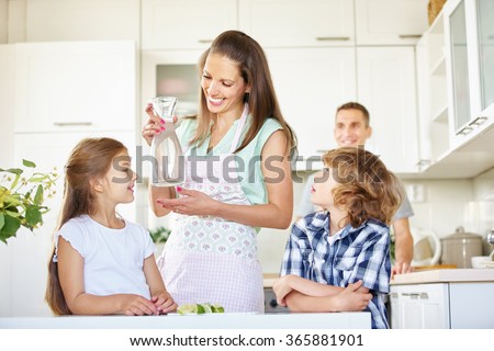 Mother and children with carafe water in the kitchen