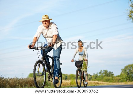 Senior couple cycling with bikes in nature in summer