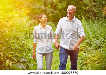 Happy senior couple taking a walk in summer in a forest