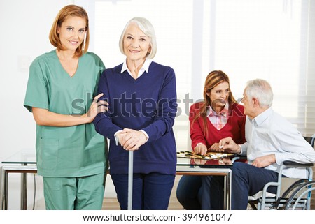 Caregiver working with happy senior people in nursing home