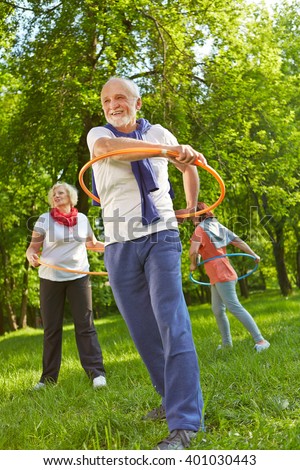 Senior group with hoops in a fitness class exercising in nature in a garden