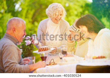 Friends and senior people celebrating birthday with cake at garden party