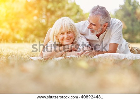 Two senior citizens relaxing in summer in the garden on a blanket