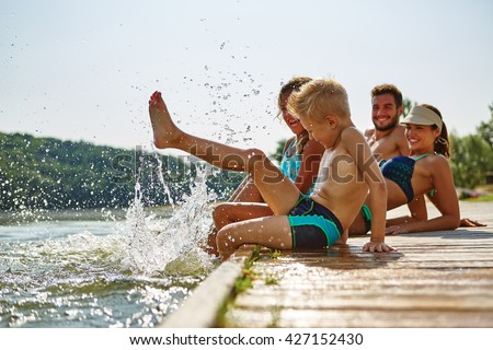 Family bathing and splashing water with their foot at a lake in summer