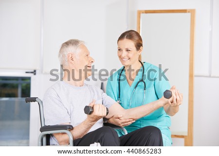 Old man in wheelchair lifting dumbbells in physiotherapy