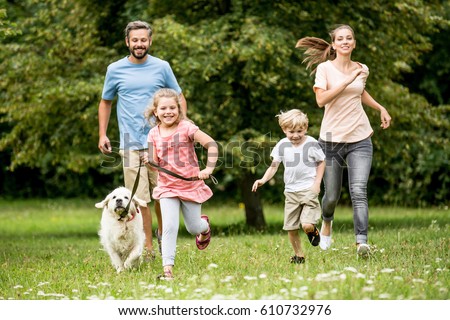 Happy children and parents with dog as family running in the nature