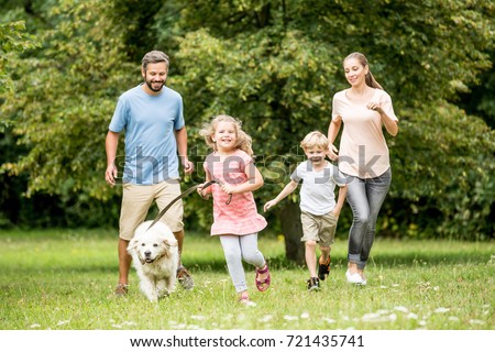Family running with dog and having fun in summer