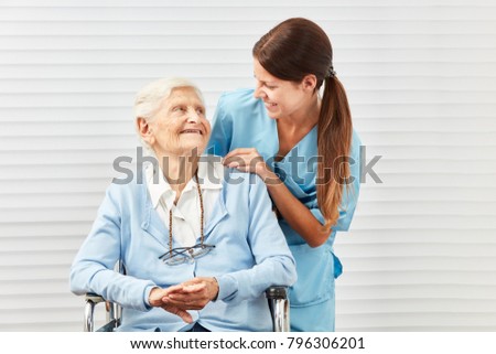 Smiling senior citizen in wheelchair and nurse at the elderly care in retirement home