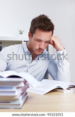University student with many books at desk learning for exams