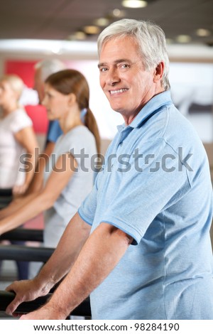 Elderly man exercising on fitness treadmill in gym
