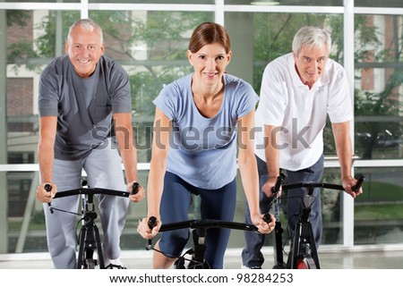 Senior fitness class in gym doing bike exercises