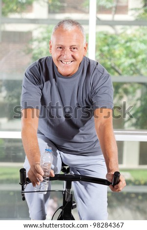 Happy senior man using a home trainer in a gym