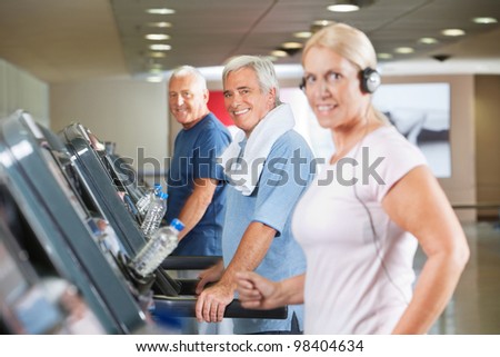 Happy senior group running on treadmills in gym