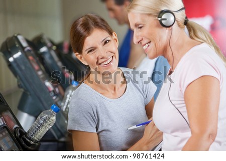 Happy fitness trainer coaching senior woman in gym