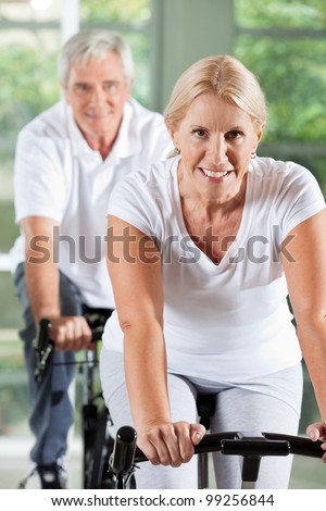 Happy senior people exercising on bikes in gym