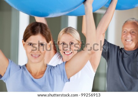 Happy seniors doing rehab exercises with gym balls in fitness center