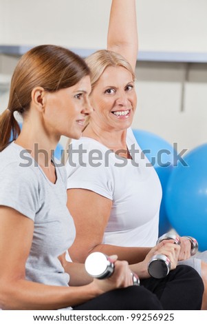 two elderly women working out with dumbbells in gym