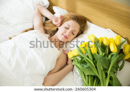 Woman sleeping in the bed and flowers on the pillow
