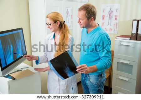 Happy female doctor with handsome male patient looking at x-ray at office. Doctor talking to her patient at office and showing radiograph.