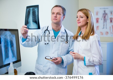 Portrait of friendly confident doctors in hospital looking at x-ray. Enthusiastic medical staff at work. Female and male doctors in diagnostics room.