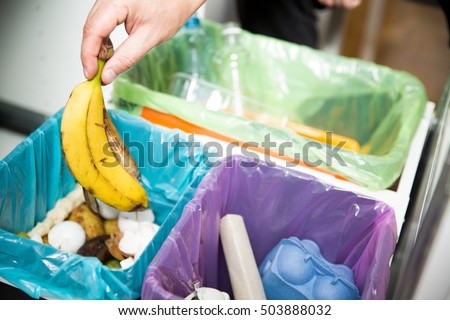 Woman putting banana peel in recycling bio bin in the kitchen. Person in the house kitchen separating waste. Different trash can with colorful garbage bags.