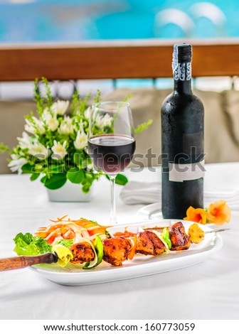 BBQ chicken on a white plate on a table with red wine Table decoration.