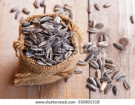 pile of sunflower seeds in the small sack on the wooden background