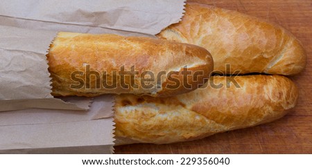 Baguettes packaged in a paper on a kitchen board