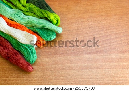 Colorful threads on a wooden background and place for message
